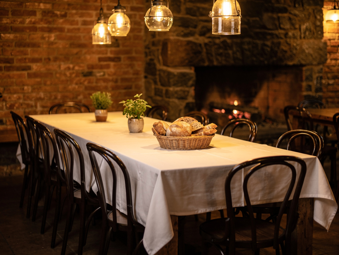 Warm candlelit main dining hall with exposed stone walls and rustic wooden tables